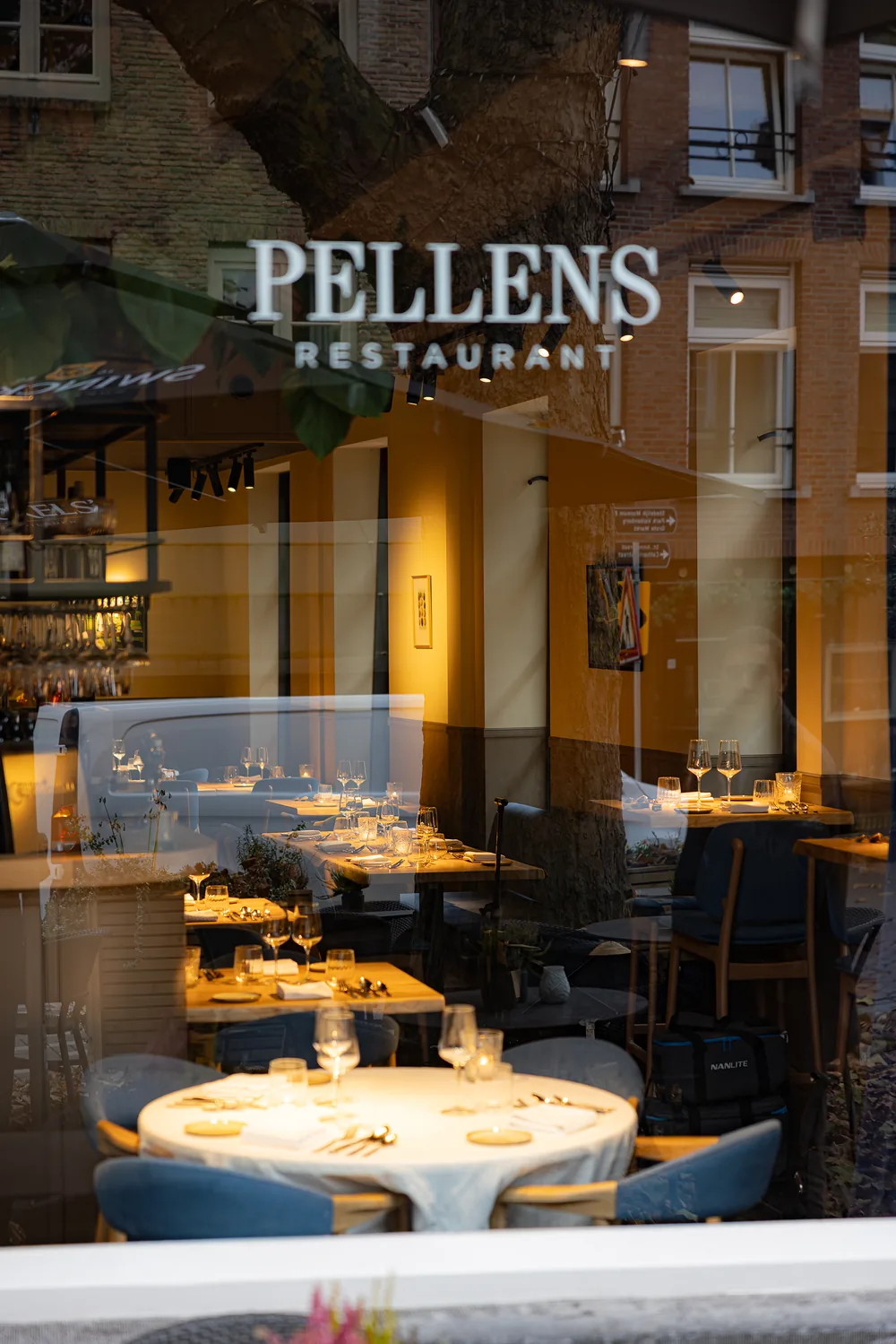 Het raam met de naam Pellens, de verlichte zaal erachter